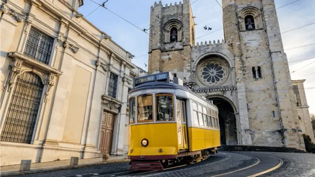 Lisbon's Sé Cathedral with the iconic yellow Tram 28 passing by