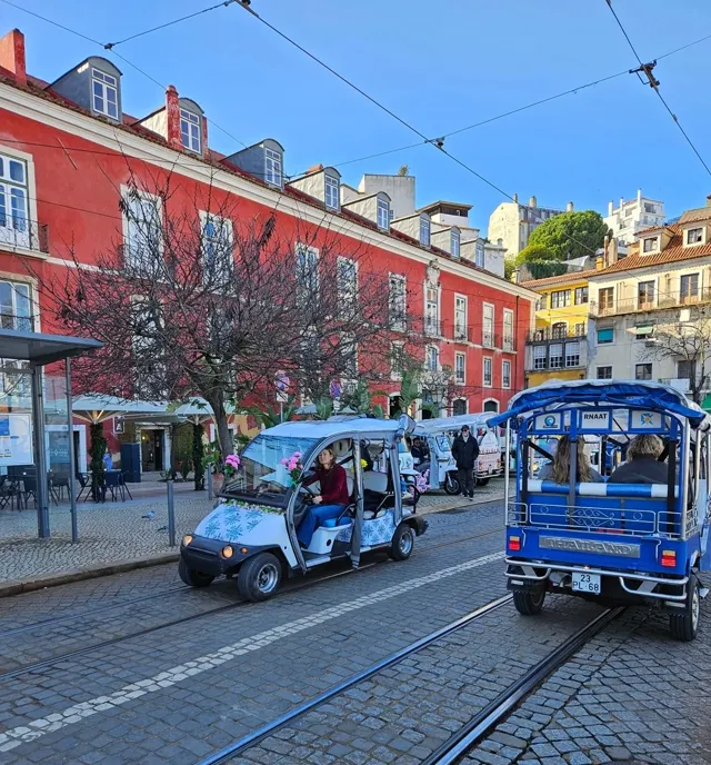 Two electric tuk-tuks next to Alfama's historic trams